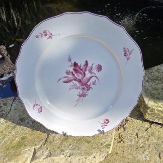 Assiette en porcelaine de Tournai polychrome à décor d'un bouquet central en camaïeu pourpre.